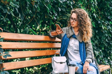 Kahve içme ve kullanma smartphone açık kıvırcık saçlı güzel kız