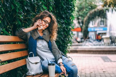 Kahve içme ve kullanma smartphone açık kıvırcık saçlı güzel kız