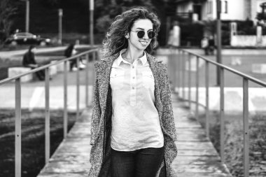 iskelede yürüyüş ve gülümseyen, siyah ve beyaz hırka giymiş kıvırcık saçlı kız