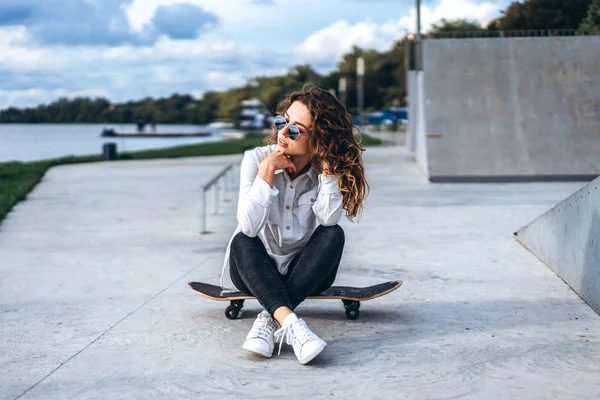 Hezká Dívka Kudrnatými Vlasy Sedí Skateboardu Parku — Stock fotografie