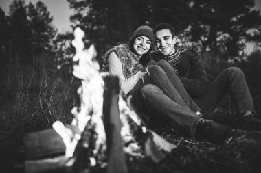 Oldukça genç çift rahatlatıcı zaman akşam, ormandaki şenlik ateşi yakın