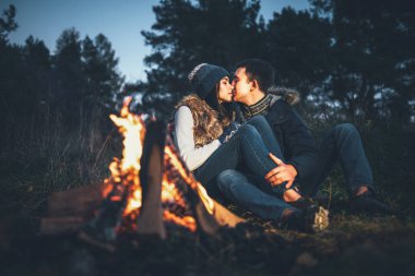 Oldukça genç çift rahatlatıcı zaman akşam, ormandaki şenlik ateşi yakın