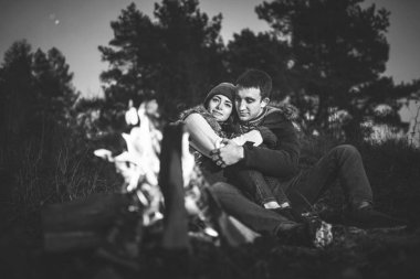 Oldukça genç çift rahatlatıcı zaman akşam, ormandaki şenlik ateşi yakın