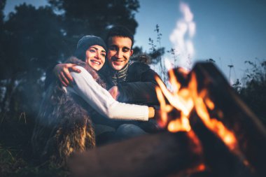 Oldukça genç çift rahatlatıcı zaman akşam, ormandaki şenlik ateşi yakın