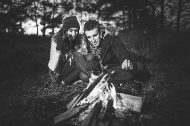 Oldukça genç çift rahatlatıcı zaman akşam, ormandaki şenlik ateşi yakın