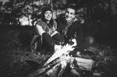 Oldukça genç çift rahatlatıcı zaman akşam, ormandaki şenlik ateşi yakın