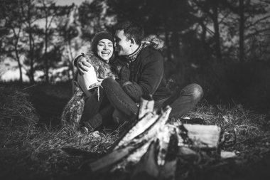 Oldukça genç çift rahatlatıcı zaman akşam, ormandaki şenlik ateşi yakın