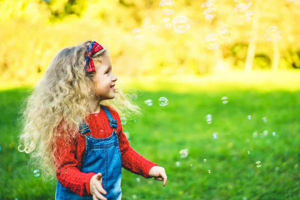 在阳光明媚的日子里 在公园里玩肥皂泡的笑容可爱的小女孩 — 图库照片