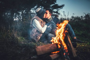 Oldukça genç çift rahatlatıcı zaman akşam, ormandaki şenlik ateşi yakın