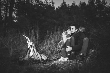 Oldukça genç çift rahatlatıcı zaman akşam, ormandaki şenlik ateşi yakın