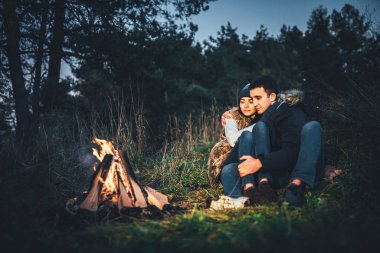 Oldukça genç çift rahatlatıcı zaman akşam, ormandaki şenlik ateşi yakın