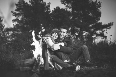 Oldukça genç çift rahatlatıcı zaman akşam, ormandaki şenlik ateşi yakın