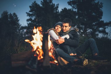 Oldukça genç çift rahatlatıcı zaman akşam, ormandaki şenlik ateşi yakın