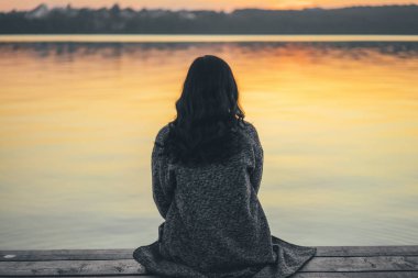 Arkadan görünüşü iskeleye yakın göl günbatımı zaman oturan uzun saçlı esmer kız