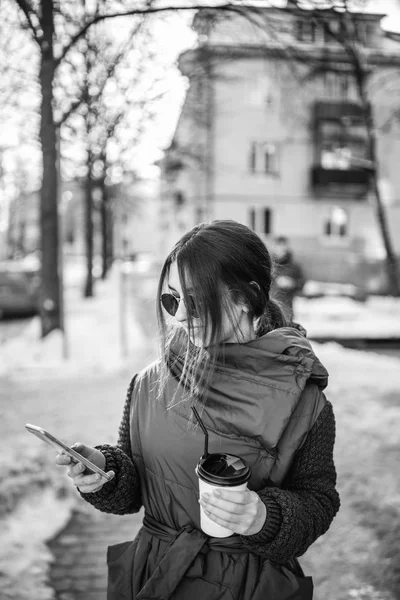 電話は 熱い飲み物と通りを歩いてきれいな女の子 — ストック写真