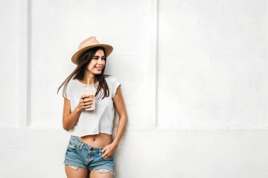 Kahve ve beyaz duvarın arkasında, kopya alanı ile şapkalı güzel esmer kız