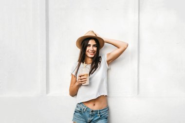 Kahve ve beyaz duvarın arkasında, kopya alanı ile şapkalı güzel esmer kız