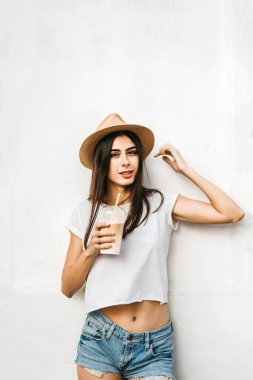 Kahve ve beyaz duvarın arkasında, kopya alanı ile şapkalı güzel esmer kız