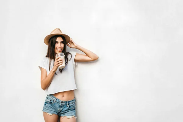 コピー スペースの後ろにコーヒーと白の壁と帽子でかなりブルネットの少女 — ストック写真