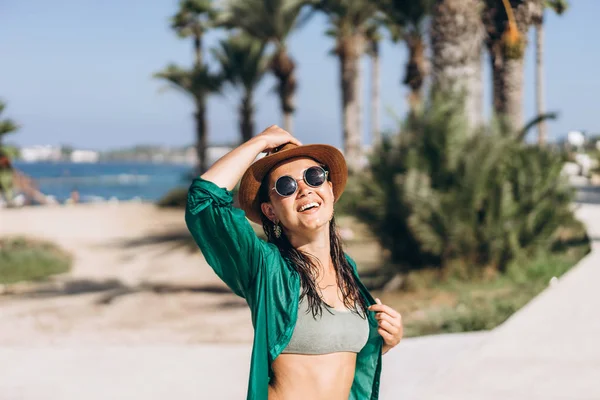 Söt pan asiatisk flicka i hatt och solglasögon i grön sarong promenader — Stockfoto