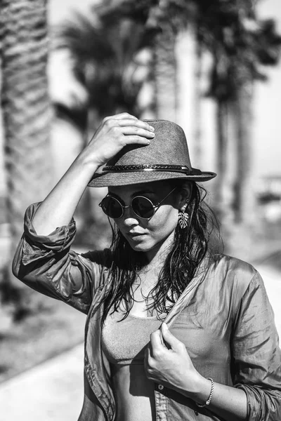 Bella ragazza bruna in cappello e occhiali da sole camminare all'aperto vicino — Foto Stock