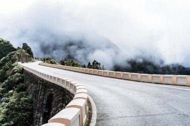 Boş yol yüksek sisli bulutlu gökyüzü ile dağlarda.