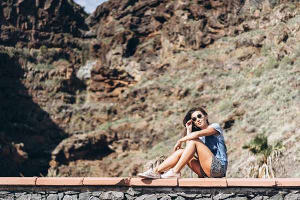 Happy hezkému turistickému tmavovláska relaxační poblíž rock. — Stock fotografie