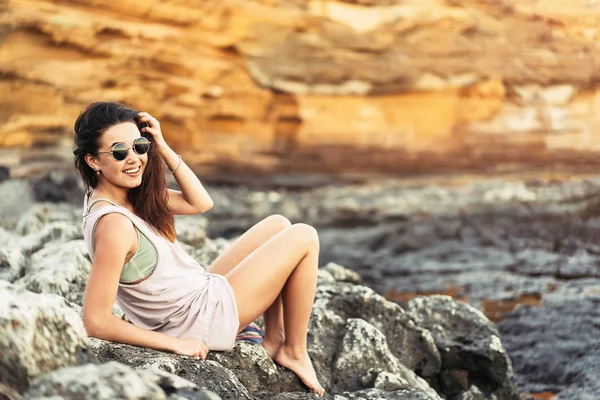 Vrij lange haren brunette toeristische meisje ontspannen op de stenen ne — Stockfoto