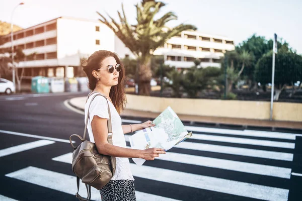 Гарненька брюнетка туристична дівчина з картою в руках на вулиці моря — стокове фото