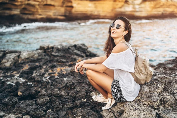 Piuttosto lunghi capelli ragazza turistica rilassante sulle pietre vicino al mare . — Foto Stock