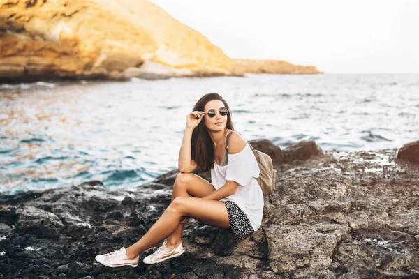 Dość długie włosy turysta dziewczyna relaksujący na kamienie w pobliżu morza. — Zdjęcie stockowe