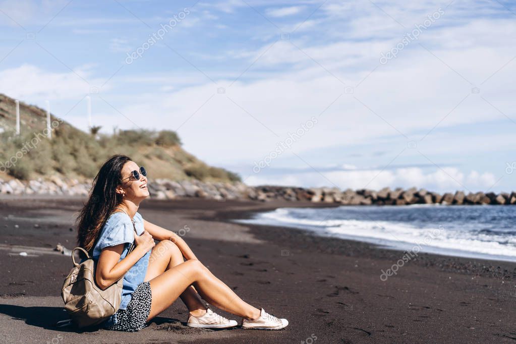 Pretty brunette long hair girl relaxing on the beach with black 