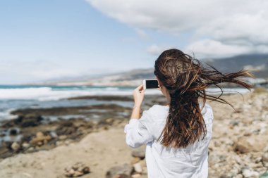 Oc yakınındaki plajda akıllı telefon ile oldukça mutlu esmer kız