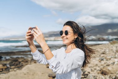 Oc yakınındaki plajda akıllı telefon ile oldukça mutlu esmer kız