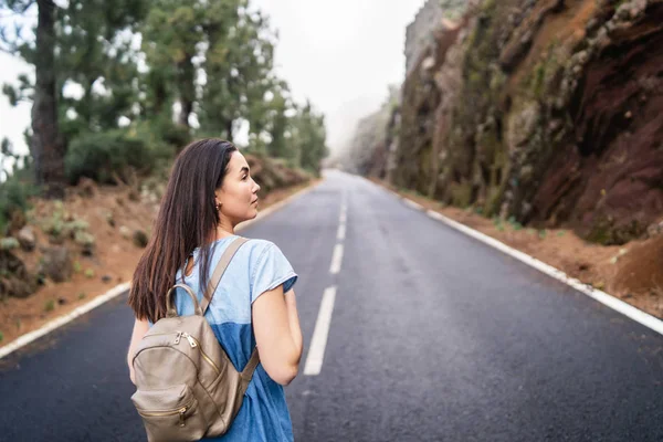 Pohled zezadu brunetka dlouhé vlasy, chůzi na mlhavé silnici — Stock fotografie