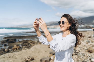 Oc yakınındaki plajda akıllı telefon ile oldukça mutlu esmer kız