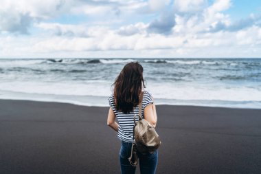 Güzel esmer kız siyah kum Sahilde yürüyüş.