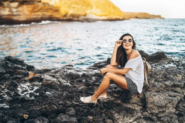 Piuttosto lunghi capelli ragazza turistica rilassante sulle pietre vicino al mare . — Foto Stock