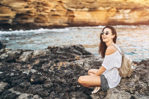 Piuttosto lunghi capelli ragazza turistica rilassante sulle pietre vicino al mare . — Foto Stock