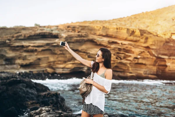 Bastante largo pelo turista chica relajarse en las piedras cerca del mar wi — Foto de Stock