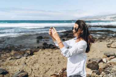 Oc yakınındaki plajda akıllı telefon ile oldukça mutlu esmer kız