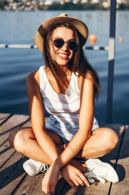 Şirin, genç, esmer kız gölün yanındaki iskelede dinleniyor..