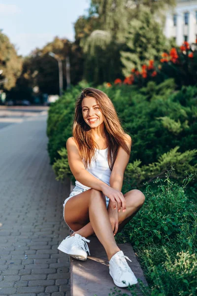 Красивая молодая улыбающаяся брюнетка расслабляется на улице — стоковое фото
