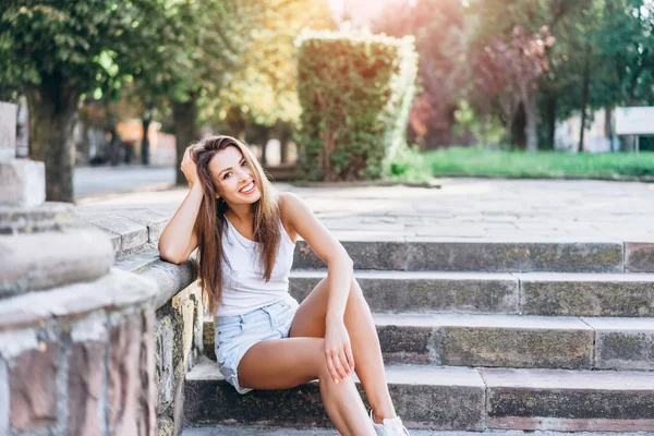 Hezká mladá usměvavá brunetka odpočívající venku na mrtvém prostoru — Stock fotografie