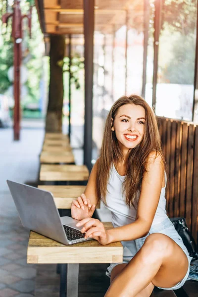 Hübsches junges Mädchen arbeitet auf Laptop in Straßencafé im Freien. — Stockfoto