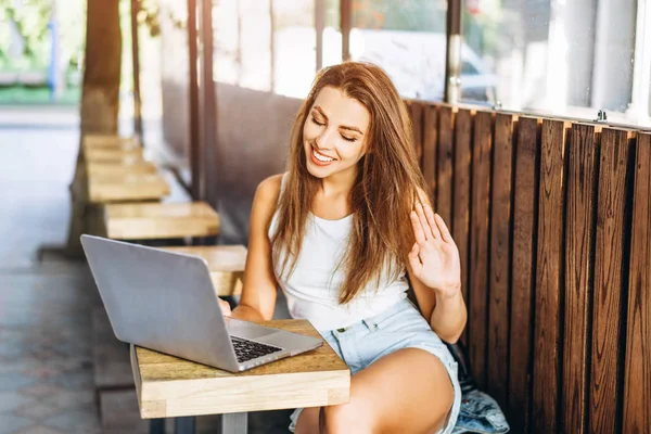 Hübsches junges Mädchen arbeitet auf Laptop in Straßencafé im Freien. — Stockfoto