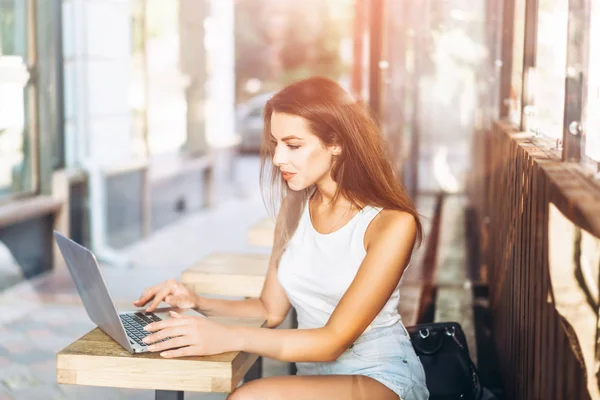 Pretty jong meisje werkt op laptop in Street Cafe outdoor. — Stockfoto