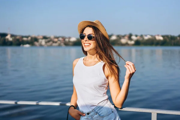 Nettes junges brünettes Mädchen entspannt sich auf der Seebrücke am See. — Stockfoto