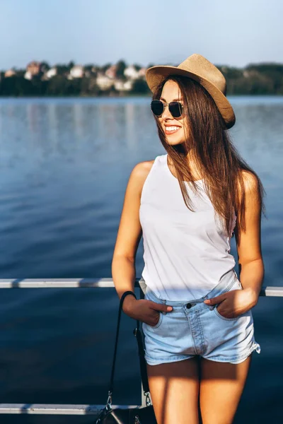 stock image Cute young brunette girl relaxing on the pier near lake.