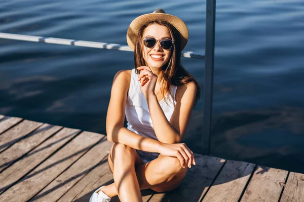 Schattig jong brunette meisje ontspannen op de pier in de buurt van meer. — Stockfoto